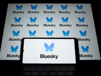 The Bluesky logo appears on a smartphone screen and as a background on a computer screen in this photo illustration in Athens, Greece, on No...