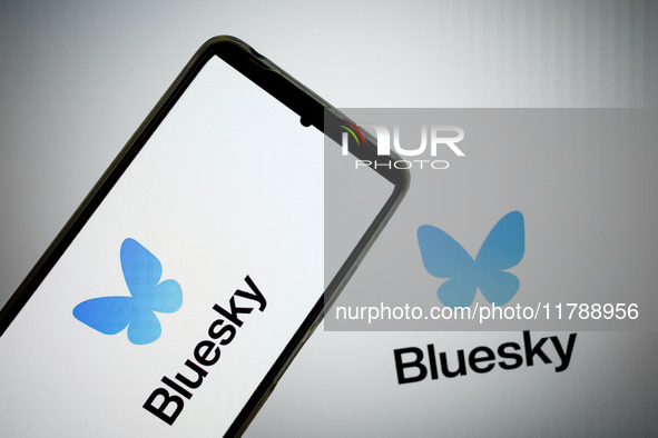 The Bluesky logo appears on a smartphone screen and as a background on a computer screen in this photo illustration in Athens, Greece, on No...