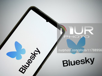 The Bluesky logo appears on a smartphone screen and as a background on a computer screen in this photo illustration in Athens, Greece, on No...