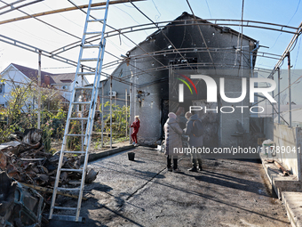 People stand outside a house damaged by a large-scale Russian missile strike in the Odesa region, southern Ukraine, on November 17, 2024. In...