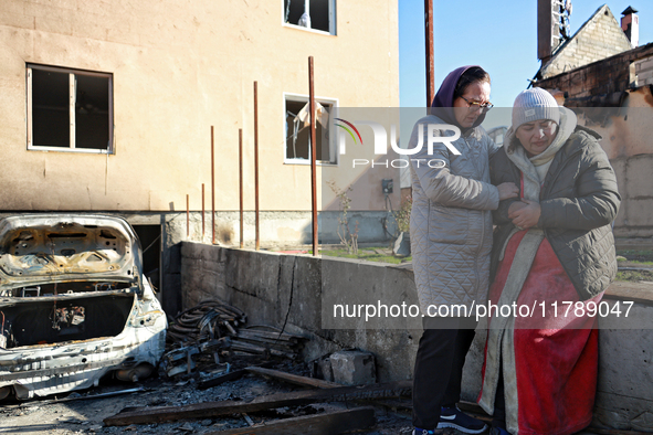 Women who survive a large-scale Russian missile strike share a hug outside a damaged house in the Odesa region, Ukraine, on November 17, 202...