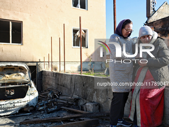 Women who survive a large-scale Russian missile strike share a hug outside a damaged house in the Odesa region, Ukraine, on November 17, 202...