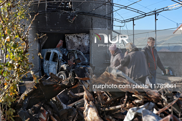 People stand near a garage with a car destroyed by a large-scale Russian missile strike in Odesa region, Ukraine, on November 17, 2024. In t...