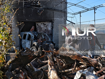 People stand near a garage with a car destroyed by a large-scale Russian missile strike in Odesa region, Ukraine, on November 17, 2024. In t...