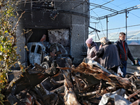 People stand near a garage with a car destroyed by a large-scale Russian missile strike in Odesa region, Ukraine, on November 17, 2024. In t...