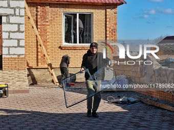 In the Odesa region, Ukraine, on November 17, 2024, a man carries a broken window pane after a large-scale Russian missile strike. In the re...