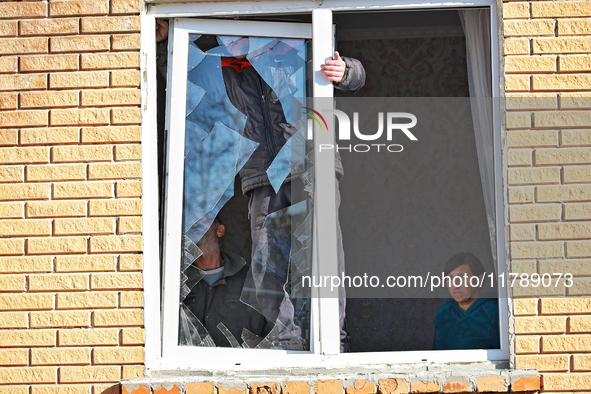 In the Odesa region, Ukraine, on November 17, 2024, a woman watches two men take down a section of a window smashed by a large-scale Russian...