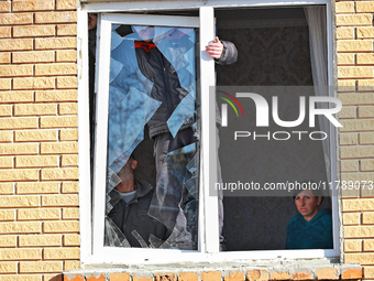 In the Odesa region, Ukraine, on November 17, 2024, a woman watches two men take down a section of a window smashed by a large-scale Russian...