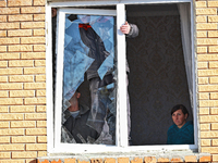 In the Odesa region, Ukraine, on November 17, 2024, a woman watches two men take down a section of a window smashed by a large-scale Russian...