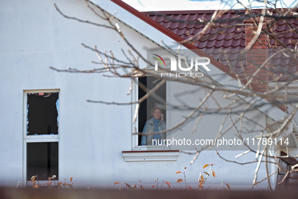 In the Odesa region, Ukraine, on November 17, 2024, a woman talks on the phone while standing in a window smashed by a large-scale Russian m...