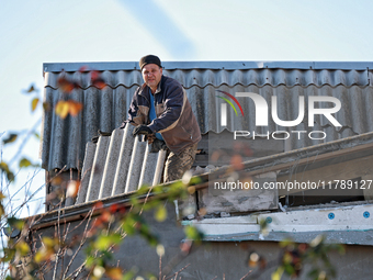 In the Odesa region, Ukraine, on November 17, 2024, a man removes broken shingle tiles from the roof of a house damaged by a large-scale Rus...