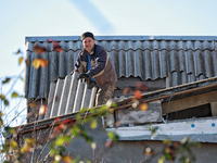 In the Odesa region, Ukraine, on November 17, 2024, a man removes broken shingle tiles from the roof of a house damaged by a large-scale Rus...