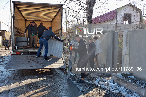 Men load broken shingle tiles into a truck at a house damaged by a large-scale Russian missile strike in the Odesa region, Ukraine, on Novem...