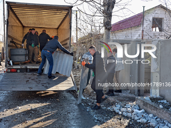 Men load broken shingle tiles into a truck at a house damaged by a large-scale Russian missile strike in the Odesa region, Ukraine, on Novem...