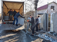 Men load broken shingle tiles into a truck at a house damaged by a large-scale Russian missile strike in the Odesa region, Ukraine, on Novem...