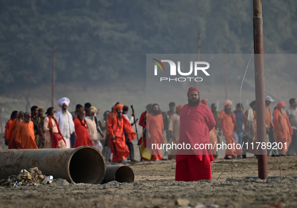 Sadhus (holy men) walk with officials on the banks of the Sangam area as they arrive for the allotment of land for the Maha Kumbh 2025 Festi...