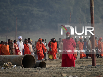 Sadhus (holy men) walk with officials on the banks of the Sangam area as they arrive for the allotment of land for the Maha Kumbh 2025 Festi...