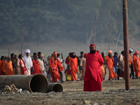 Sadhus (holy men) walk with officials on the banks of the Sangam area as they arrive for the allotment of land for the Maha Kumbh 2025 Festi...