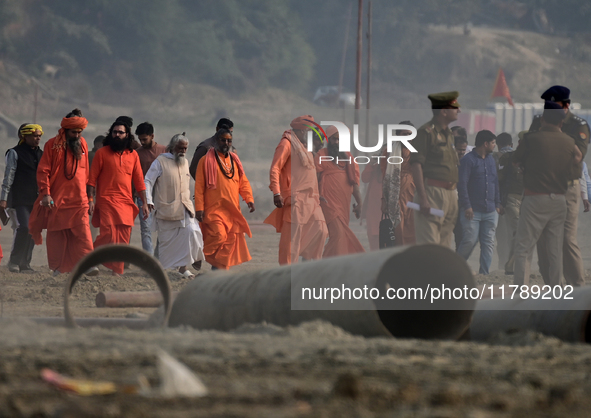 Sadhus (holy men) walk with officials on the banks of the Sangam area as they arrive for the allotment of land for the Maha Kumbh 2025 Festi...