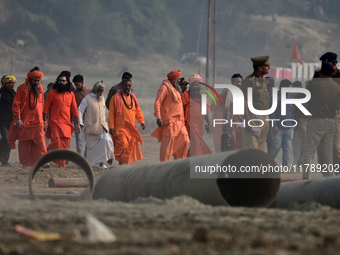 Sadhus (holy men) walk with officials on the banks of the Sangam area as they arrive for the allotment of land for the Maha Kumbh 2025 Festi...