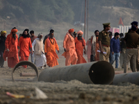 Sadhus (holy men) walk with officials on the banks of the Sangam area as they arrive for the allotment of land for the Maha Kumbh 2025 Festi...