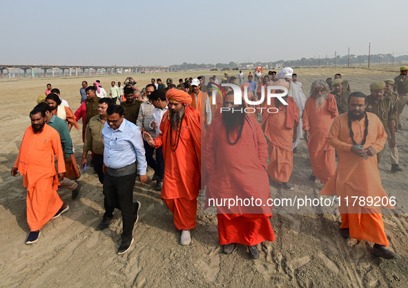 Sadhus (holy men) walk with officials on the banks of the Sangam area as they arrive for the allotment of land for the Maha Kumbh 2025 Festi...