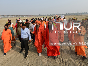 Sadhus (holy men) walk with officials on the banks of the Sangam area as they arrive for the allotment of land for the Maha Kumbh 2025 Festi...