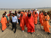 Sadhus (holy men) walk with officials on the banks of the Sangam area as they arrive for the allotment of land for the Maha Kumbh 2025 Festi...