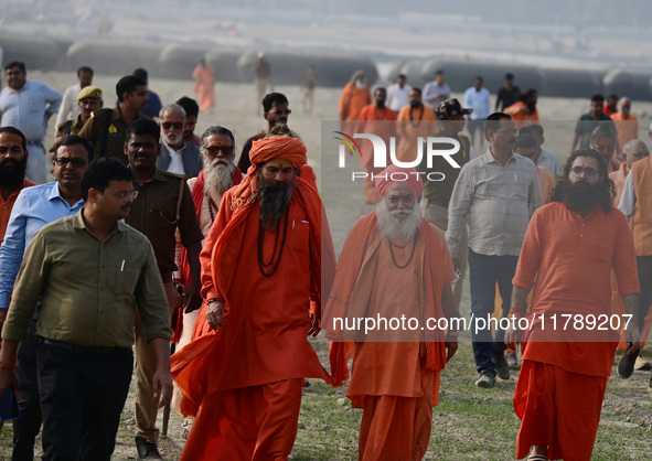 Sadhus (holy men) walk with officials on the banks of the Sangam area as they arrive for the allotment of land for the Maha Kumbh 2025 Festi...