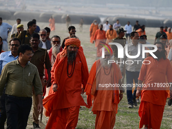 Sadhus (holy men) walk with officials on the banks of the Sangam area as they arrive for the allotment of land for the Maha Kumbh 2025 Festi...