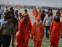 Sadhus (holy men) walk with officials on the banks of the Sangam area as they arrive for the allotment of land for the Maha Kumbh 2025 Festi...