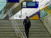 A traveler walks up the stairs to Platform 9 at Arnhem Centraal Station in Arnhem, Netherlands, on July 27, 2023. The signage above displays...