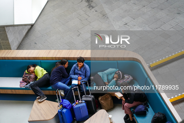 Tired travelers rest at Arnhem Central Station in Arnhem, Netherlands, on July 27, 2023. Some of them lie down on the curved seating, using...