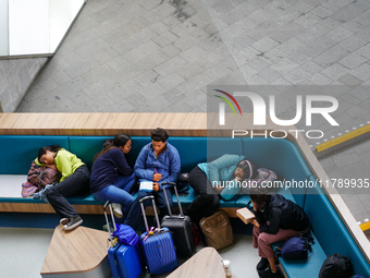 Tired travelers rest at Arnhem Central Station in Arnhem, Netherlands, on July 27, 2023. Some of them lie down on the curved seating, using...