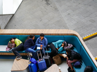 Tired travelers rest at Arnhem Central Station in Arnhem, Netherlands, on July 27, 2023. Some of them lie down on the curved seating, using...