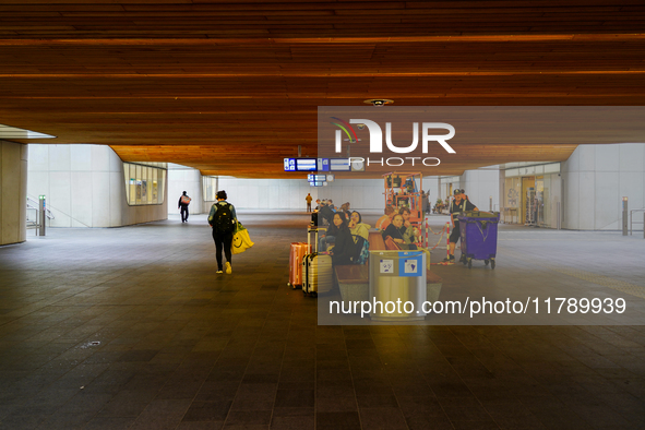 Passengers wait on benches with their luggage under the wooden-paneled ceiling of Arnhem Centraal Station in the Netherlands, on July 27, 20...