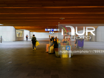 Passengers wait on benches with their luggage under the wooden-paneled ceiling of Arnhem Centraal Station in the Netherlands, on July 27, 20...