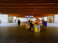 Passengers wait on benches with their luggage under the wooden-paneled ceiling of Arnhem Centraal Station in the Netherlands, on July 27, 20...