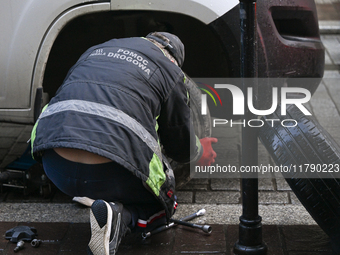 KRAKOW, POLAND - NOVEMBER 18:   
Member of roadside assistance (Polish: Pomoc Drogowa) changing a tire on a car parked in Krakow's Old Town,...