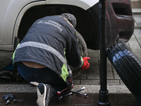 KRAKOW, POLAND - NOVEMBER 18:   
Member of roadside assistance (Polish: Pomoc Drogowa) changing a tire on a car parked in Krakow's Old Town,...