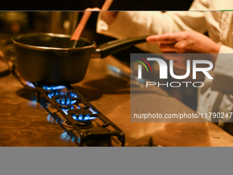 KRAKOW, POLAND - NOVEMBER 18:   
Staff member melting chocolate over natural gas burners on a stove in a Krakow cafe, showcasing the role of...