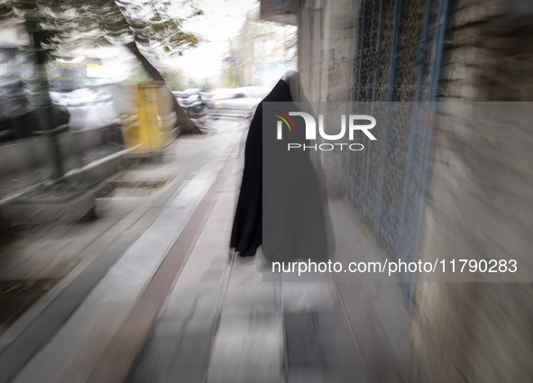 A veiled Iranian woman walks along a sidewalk in downtown Tehran, Iran, on November 17, 2024. 