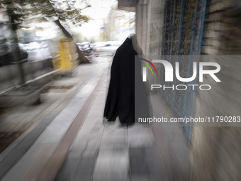 A veiled Iranian woman walks along a sidewalk in downtown Tehran, Iran, on November 17, 2024. (