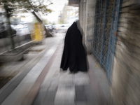 A veiled Iranian woman walks along a sidewalk in downtown Tehran, Iran, on November 17, 2024. (