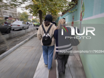 Two young Iranian women, one of whom is not wearing a mandatory headscarf, walk together along a sidewalk in downtown Tehran, Iran, on Novem...