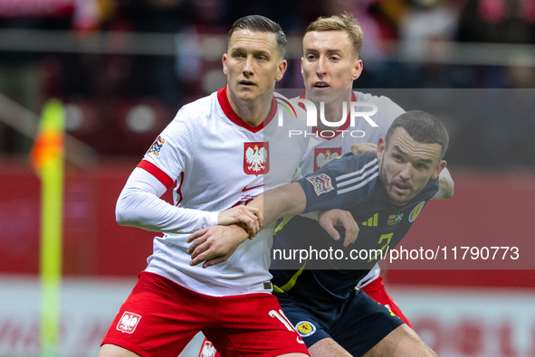 Piotr Zielinski, Adam Buksa and John McGinn in action during the  UEFA Nations League 2024 League A Group A1 match between Poland and Scotla...