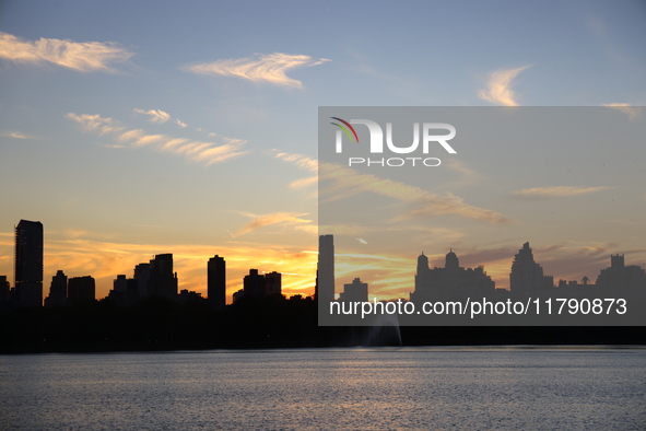 The sunset appears in the west across the Jacqueline Kennedy Onassis Reservoir in Central Park while the fall weather occurs in New York, N....