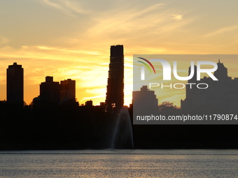 The sunset appears in the west across the Jacqueline Kennedy Onassis Reservoir in Central Park while the fall weather occurs in New York, N....