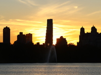 The sunset appears in the west across the Jacqueline Kennedy Onassis Reservoir in Central Park while the fall weather occurs in New York, N....