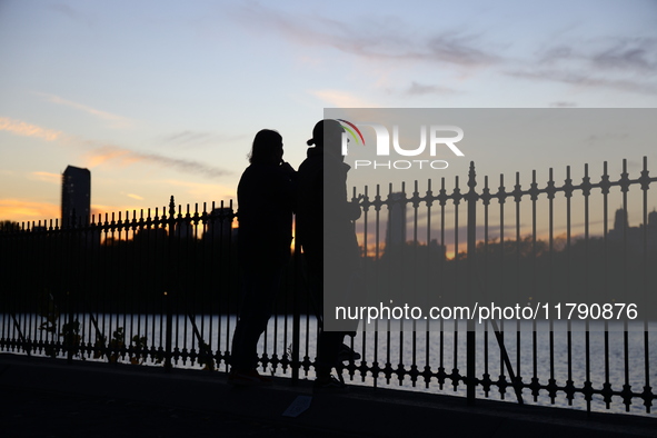 People take photos of the Jacqueline Kennedy Onassis Reservoir in Central Park while experiencing the fall weather in New York, N.Y., on Nov...